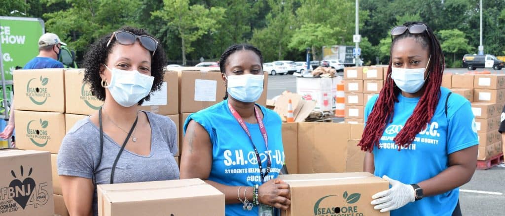 Volunteers in masks holding boxes of food