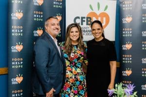 Carlos Rodriguez, Natalie Pasquarella, and Soledad O'Brien stand in front of CFBNJ banner