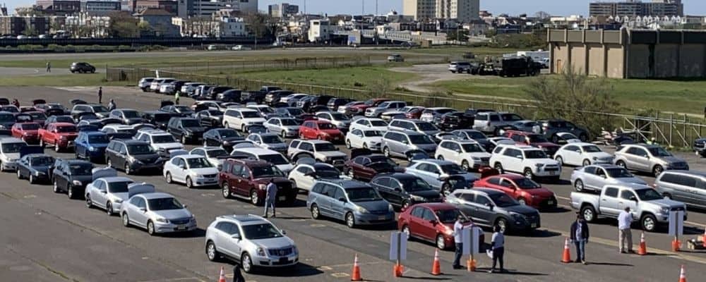 Cars line up in a parking lot to receive food with Atlantic City in the background