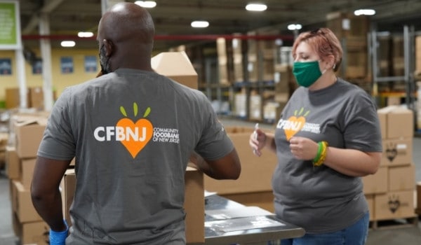 Volunteers in gray shirts pack boxes at a warehouse