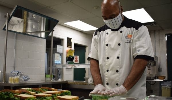 Chef in a white coat putting together sandwiches in a kitchen