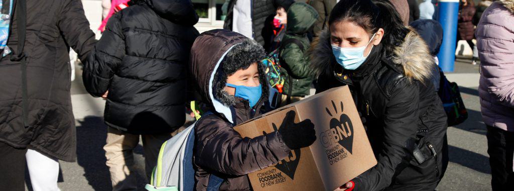 Woman ahanding child a box of food