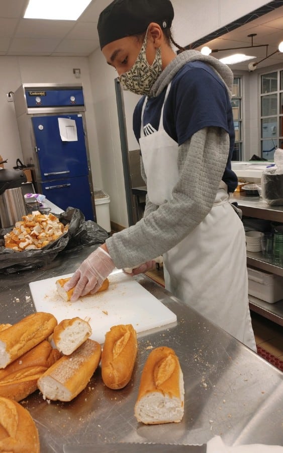 Person cutting bread on a cutting board in an industrial kitchen