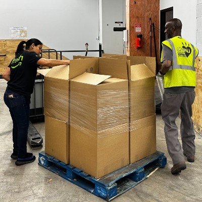 Man and woman unwrapping a pallet of boxes